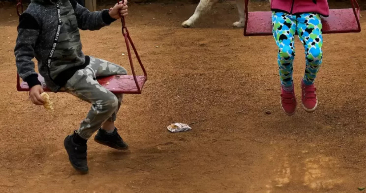 Niños en un patio usando columpios
