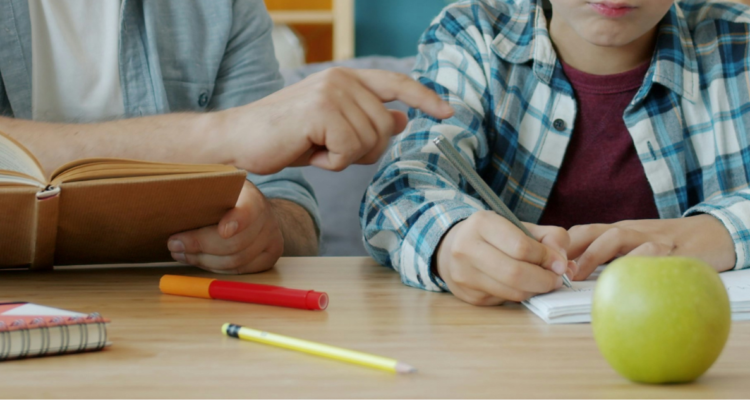 Papá ayudando a estudiar a hijo.