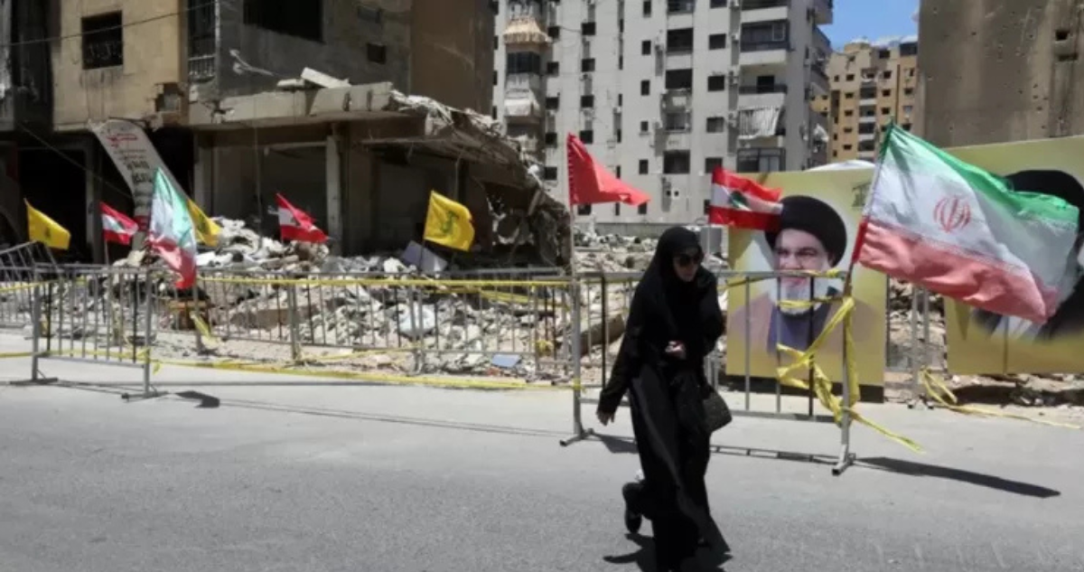 Una mujer camina por una calle de Beirut en medio de banderas e imágenes alusivas a Irán y Hezbolá.