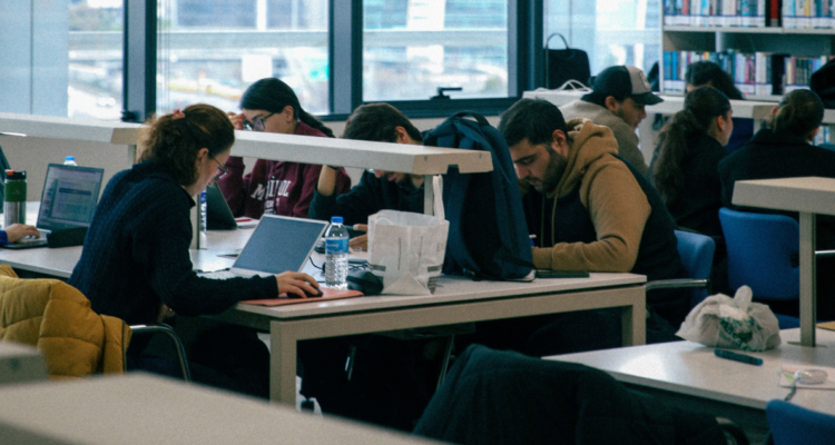 Foto de contexto de estudiantes universitarios en una biblioteca.