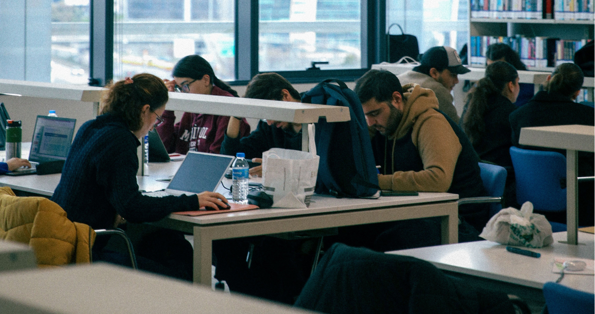 Foto de contexto de estudiantes universitarios en una biblioteca.