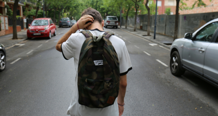 Joven con mochila caminando por una calle