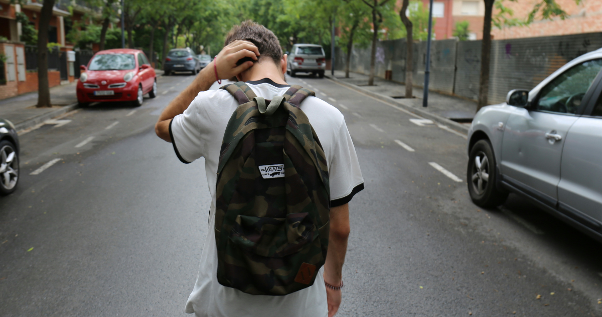 Joven con mochila caminando por una calle