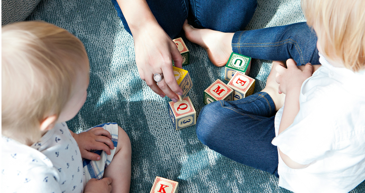 Adulto jugando con niños de diferentes edades.