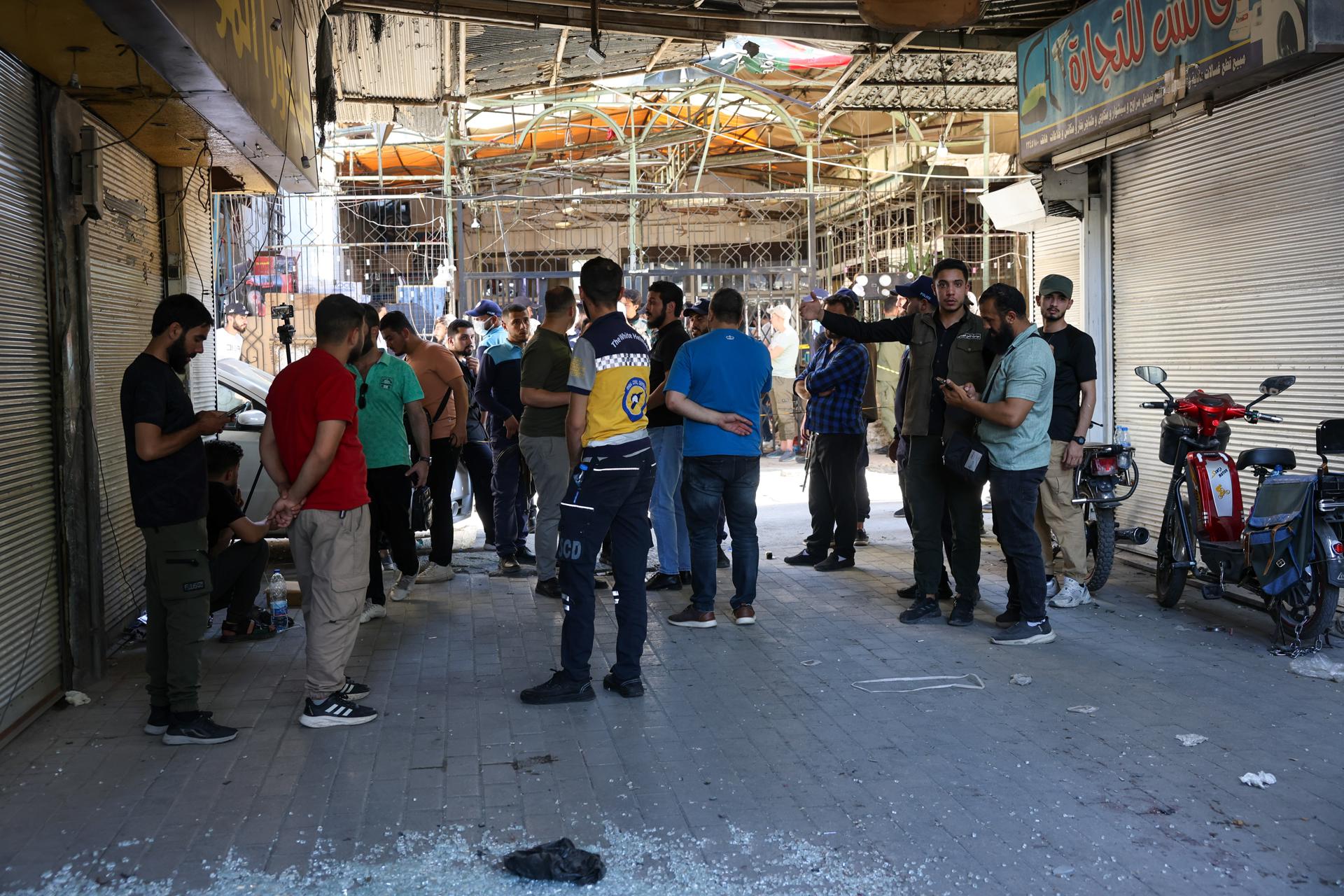 Miembros de las fuerzas de seguridad sirias y civiles en el lugar donde se produjo la explosión en Damasco
