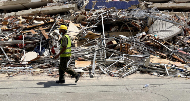 Un hombre camina frente a escombros de una edificación derrumbada por terremotos en La Guaira, Venezuela