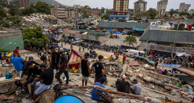 Personas observan edificios colapsados por los terremotos este martes, en La Guaira (Venezuela)