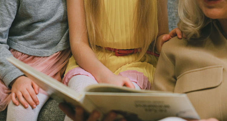 Niños y un adulto leyendo un libro.