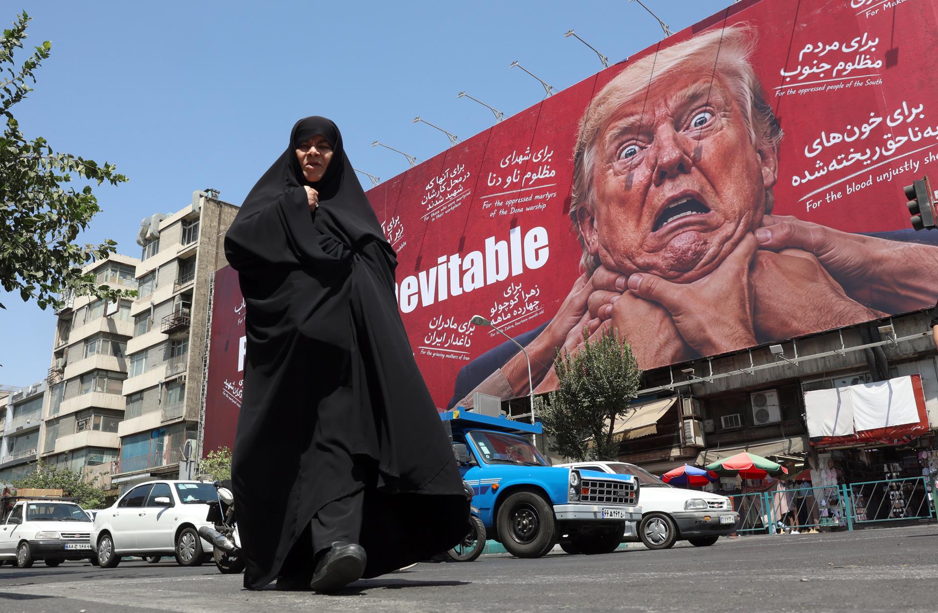 Una mujer camina junto a una valla publicitaria contra Donald Trump en Teherán, Irán