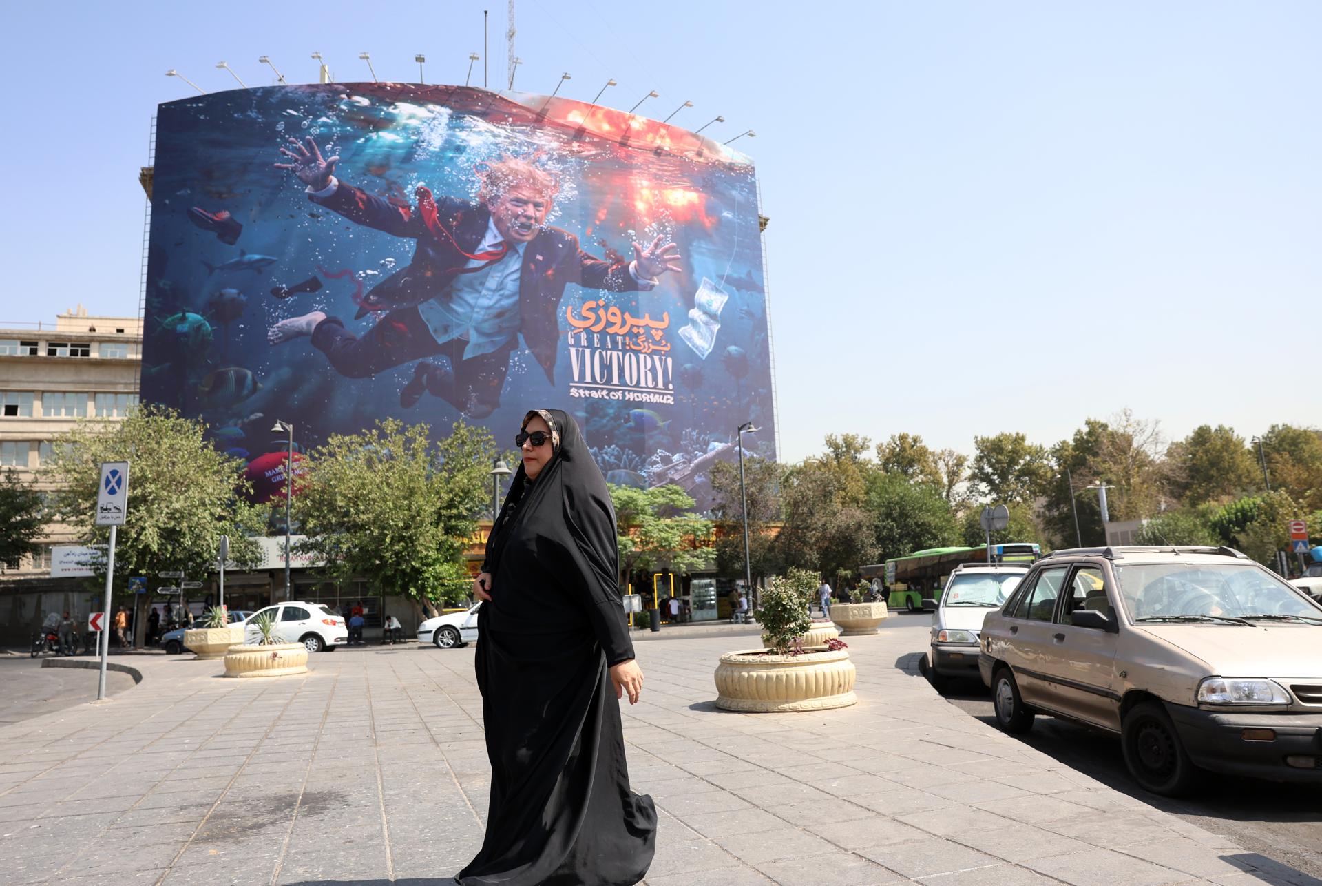 Una mujer iraní pasa junto a una valla publicitaria anti EEUU en Teherán que muestra al presidente Donald Trump