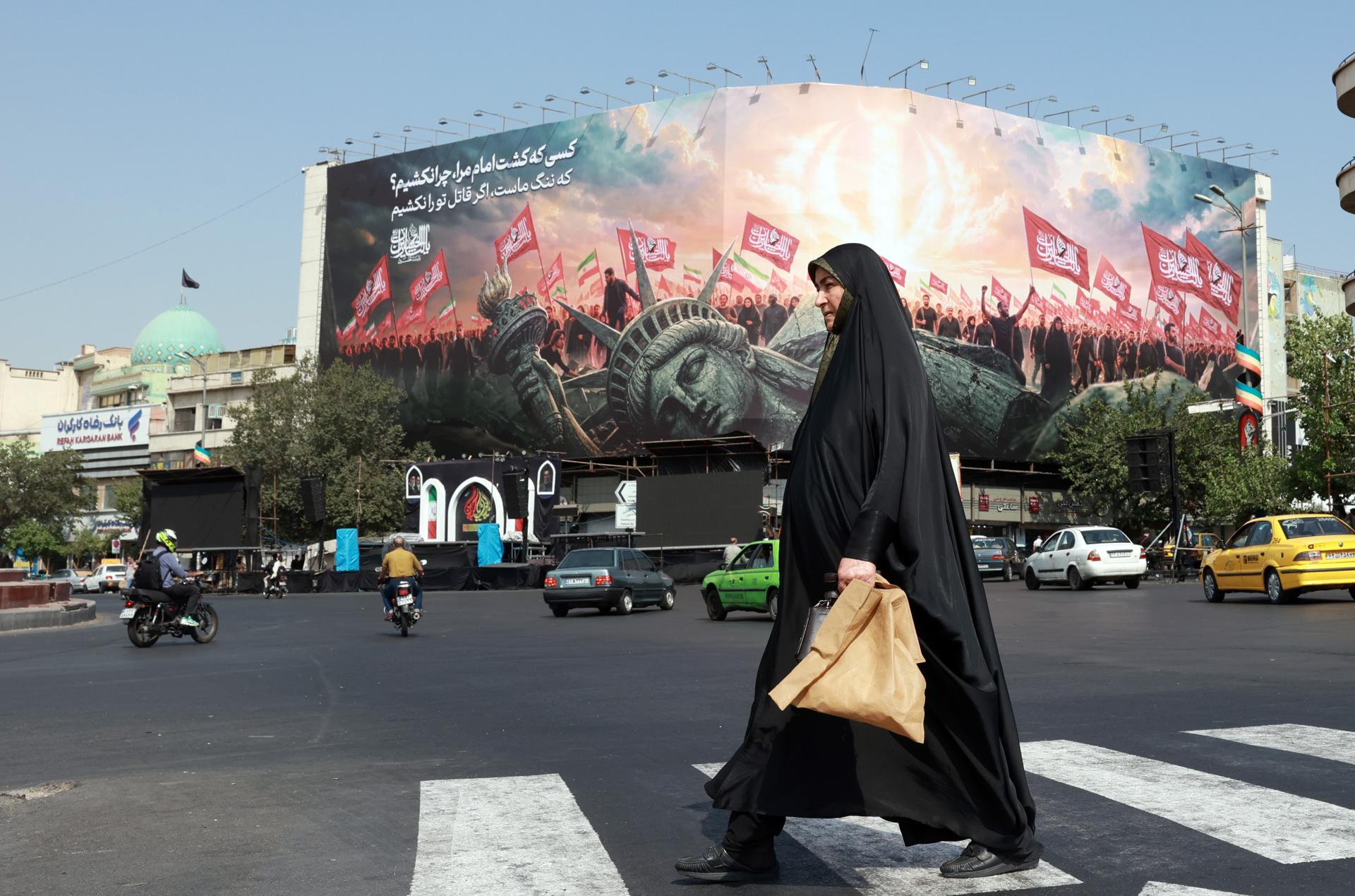 Una mujer iraní pasa junto a una valla publicitaria antiestadounidense en la plaza Enghelab de Teherán