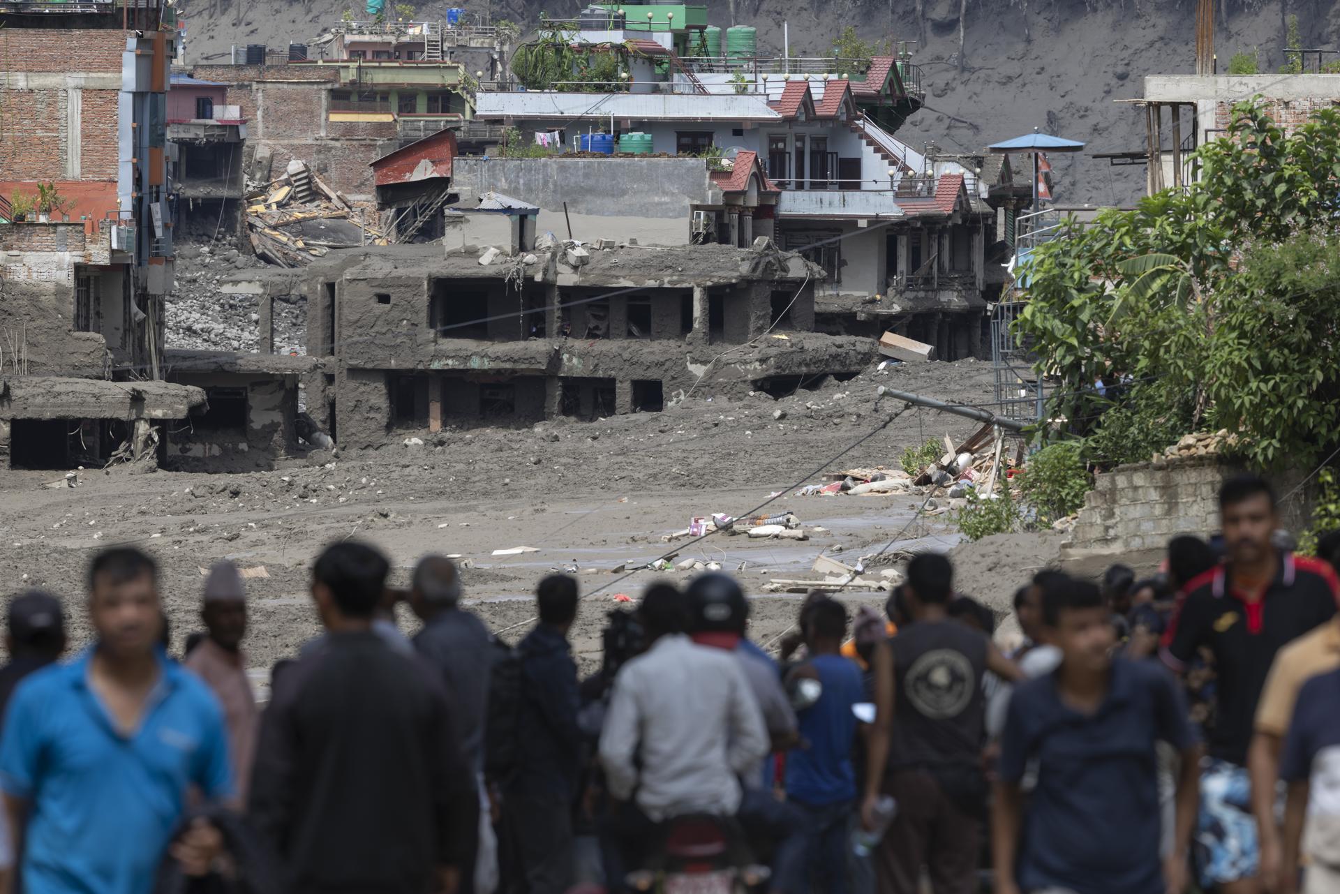 Personas observan cómo las aguas de la crecida arrasan Trishuli Bazar tras la inundación en el distrito de Nuwakot, Nepal