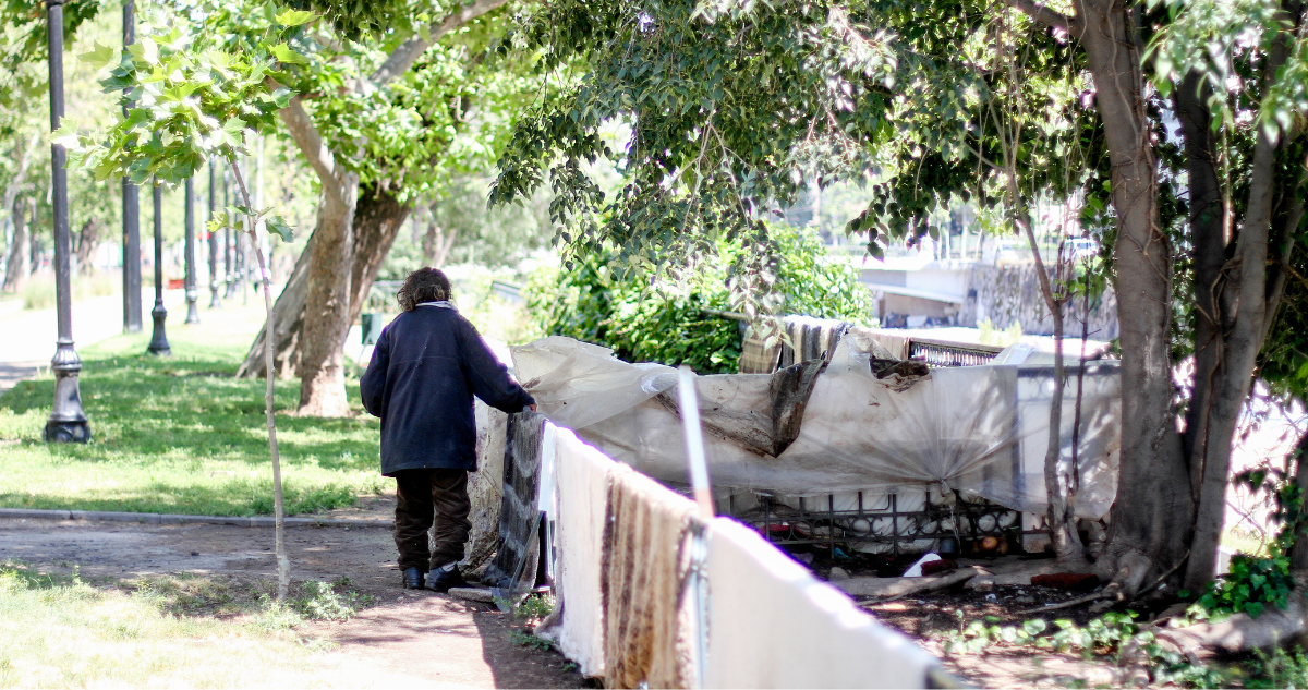 Persona en situación de calle junto a un ruco.