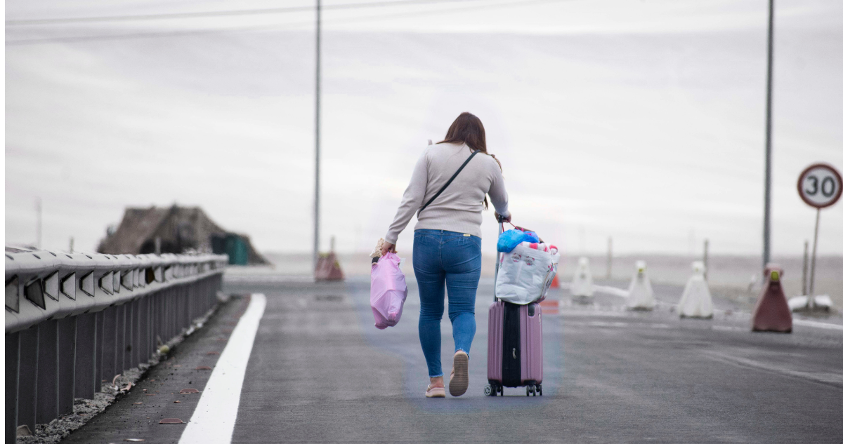 Migrante con sus maletas en la frontera.
