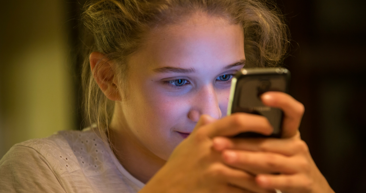 Imagen de una adolescente usando su teléfono para ilustrar nota sobre los chatbots