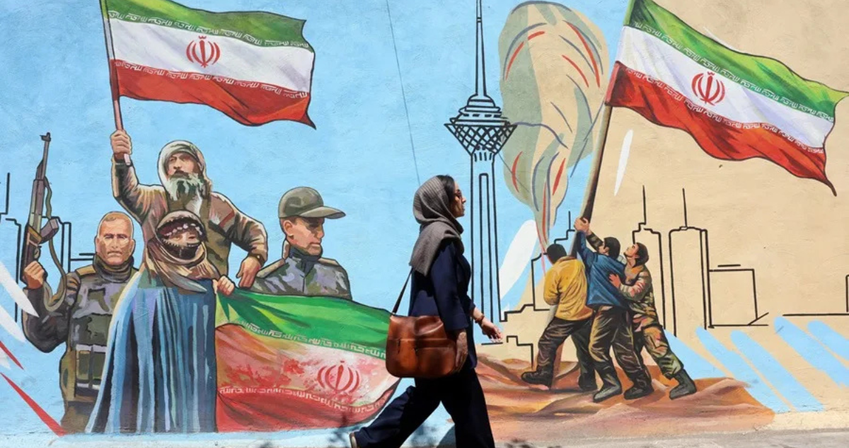 Una mujer camina delante de un mural en Teherán