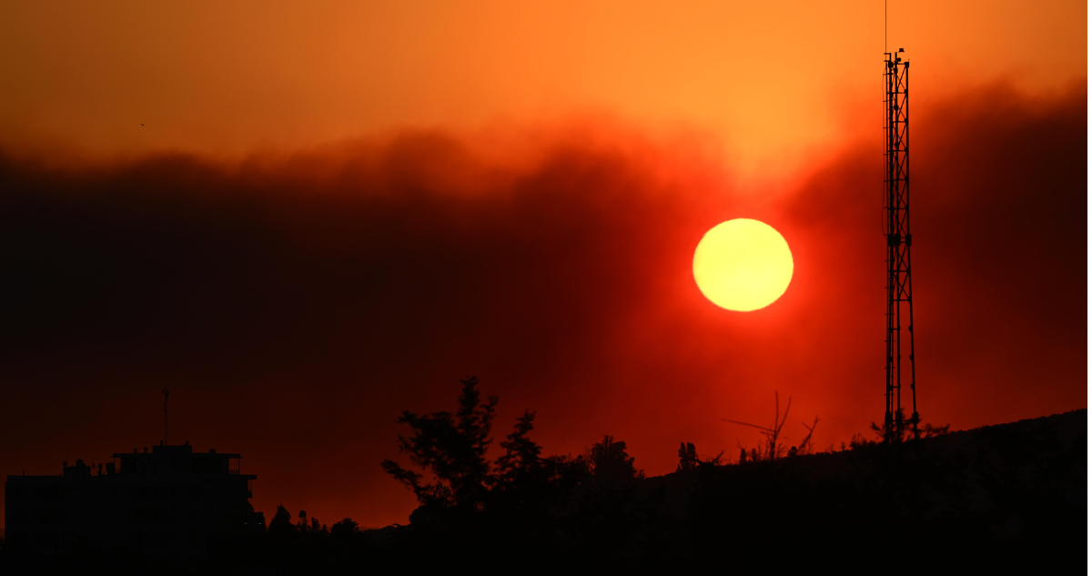 Foto de archivo de sol teñido de rojo durante incendio forestal.