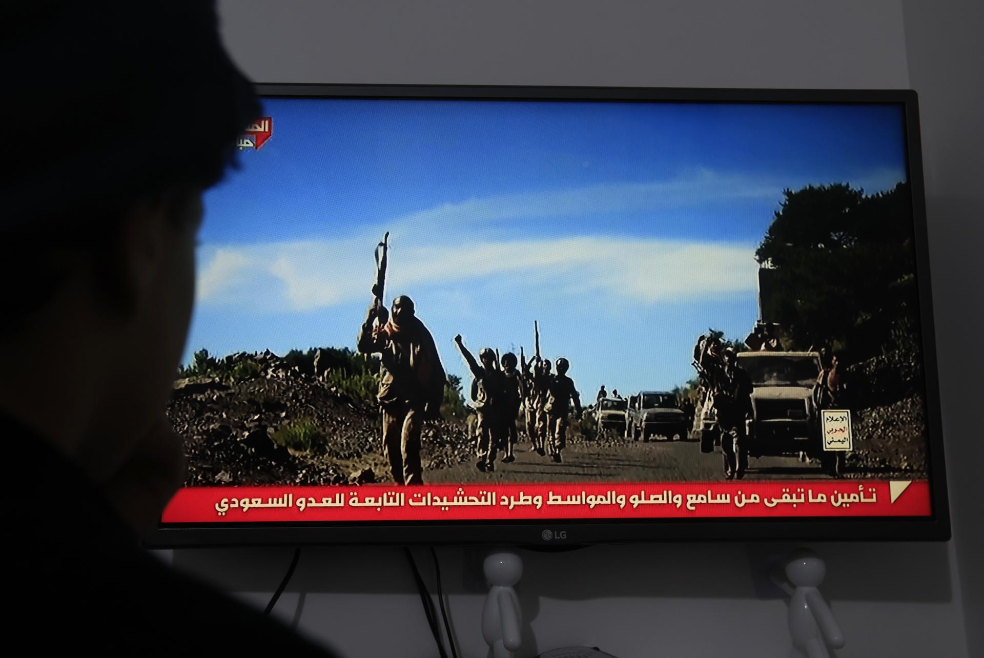 Una persona observa una transmisión televisiva que muestra a combatientes hutíes en Saná, Yemen.
