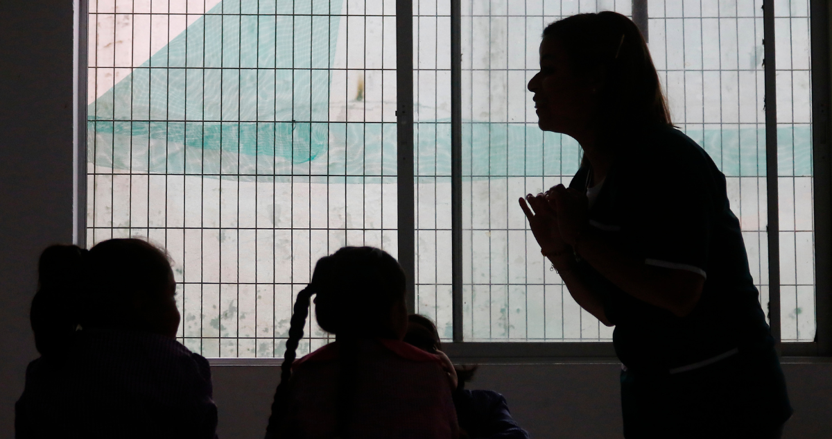 Profesora y alumnos en sombras.