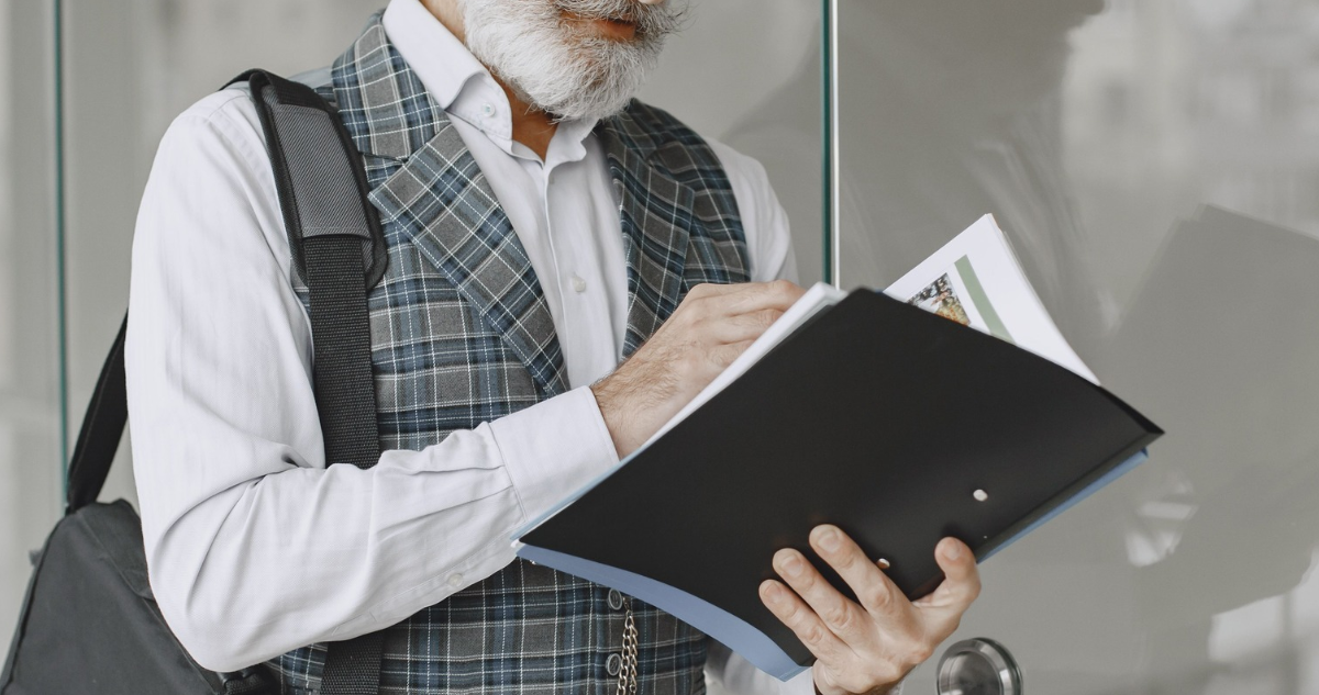 Hombre con canas portando una carpeta