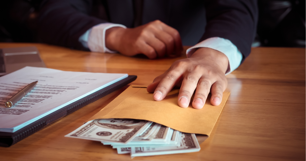 Mano de persona encima de un sobre con dinero.
