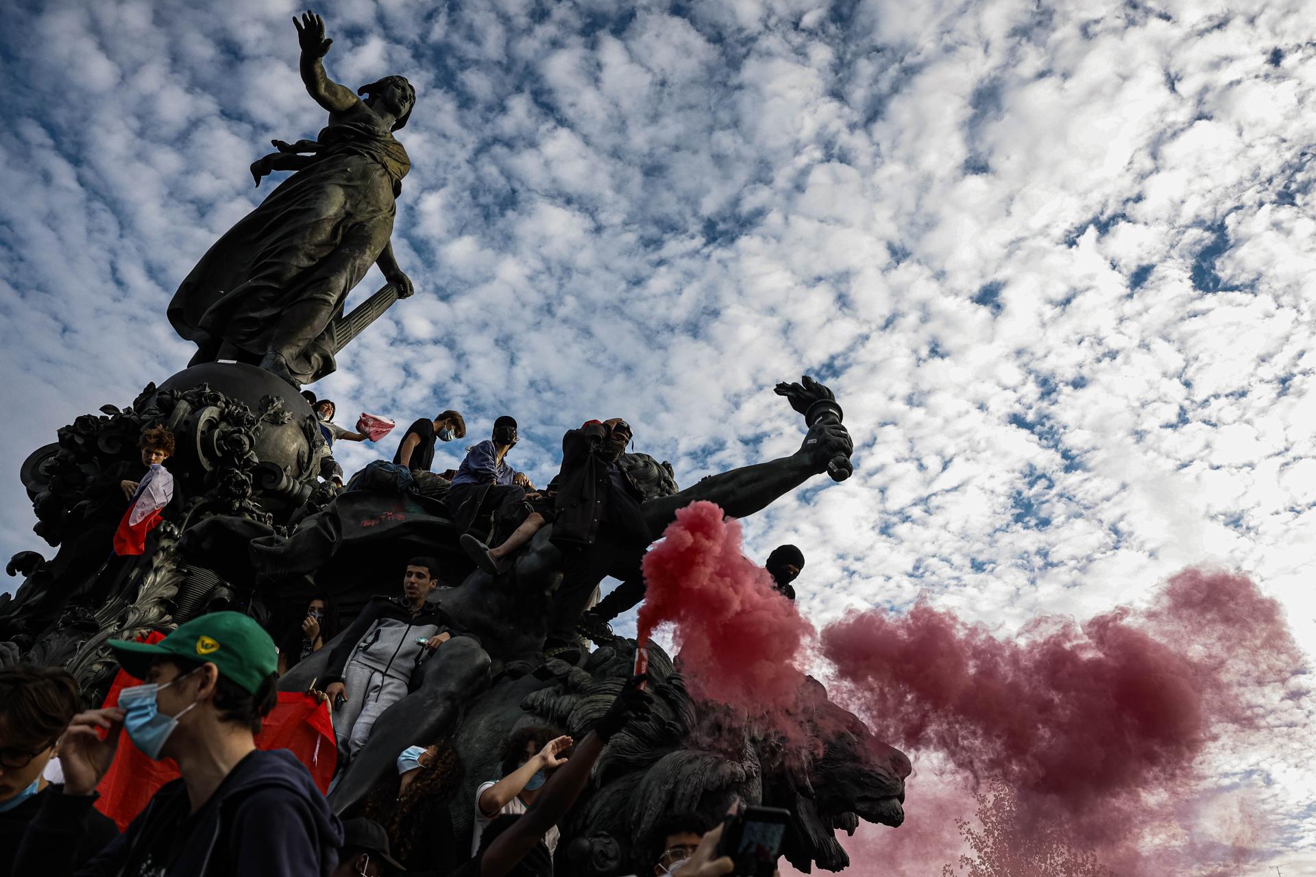 Estudiantes disparan bengalas de humo rojo durante una jornada de protestas en la Plaza de la República en París